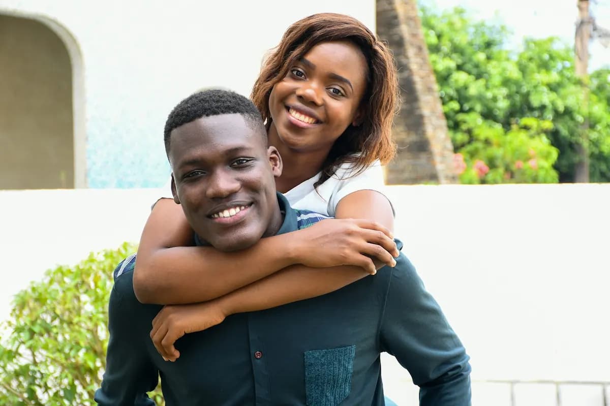 Un couple rit, elle le serre dans ses bras par derrière