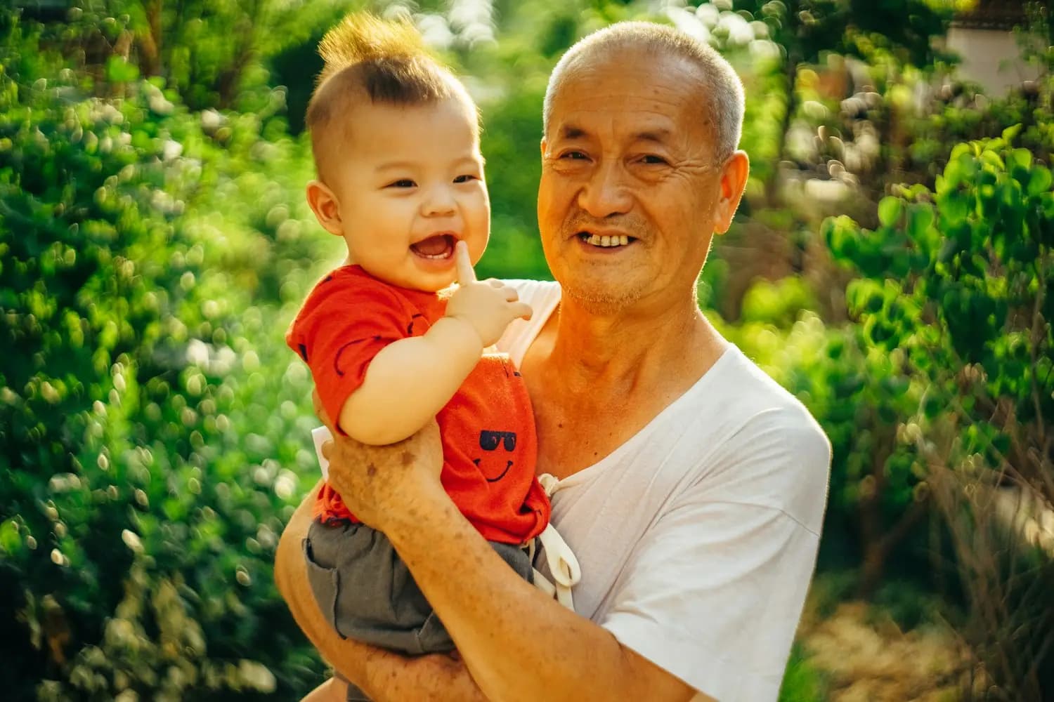 A grandfather smiles with a baby in his arms