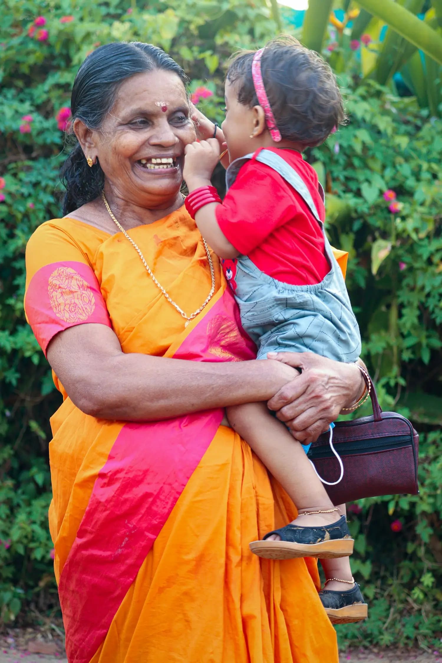 A grandmother in a sari holds a child