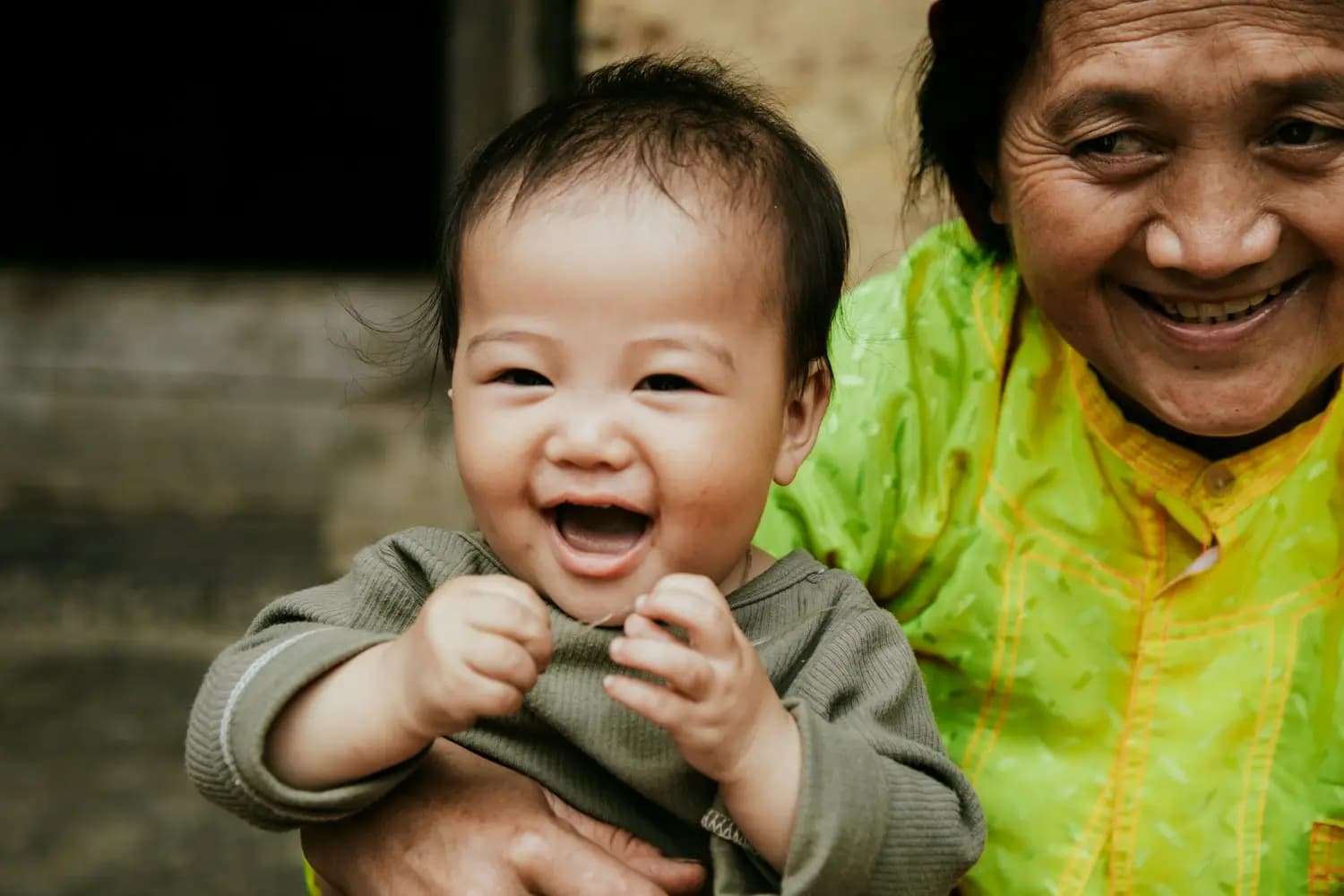 A baby laughing in an older woman’s arms