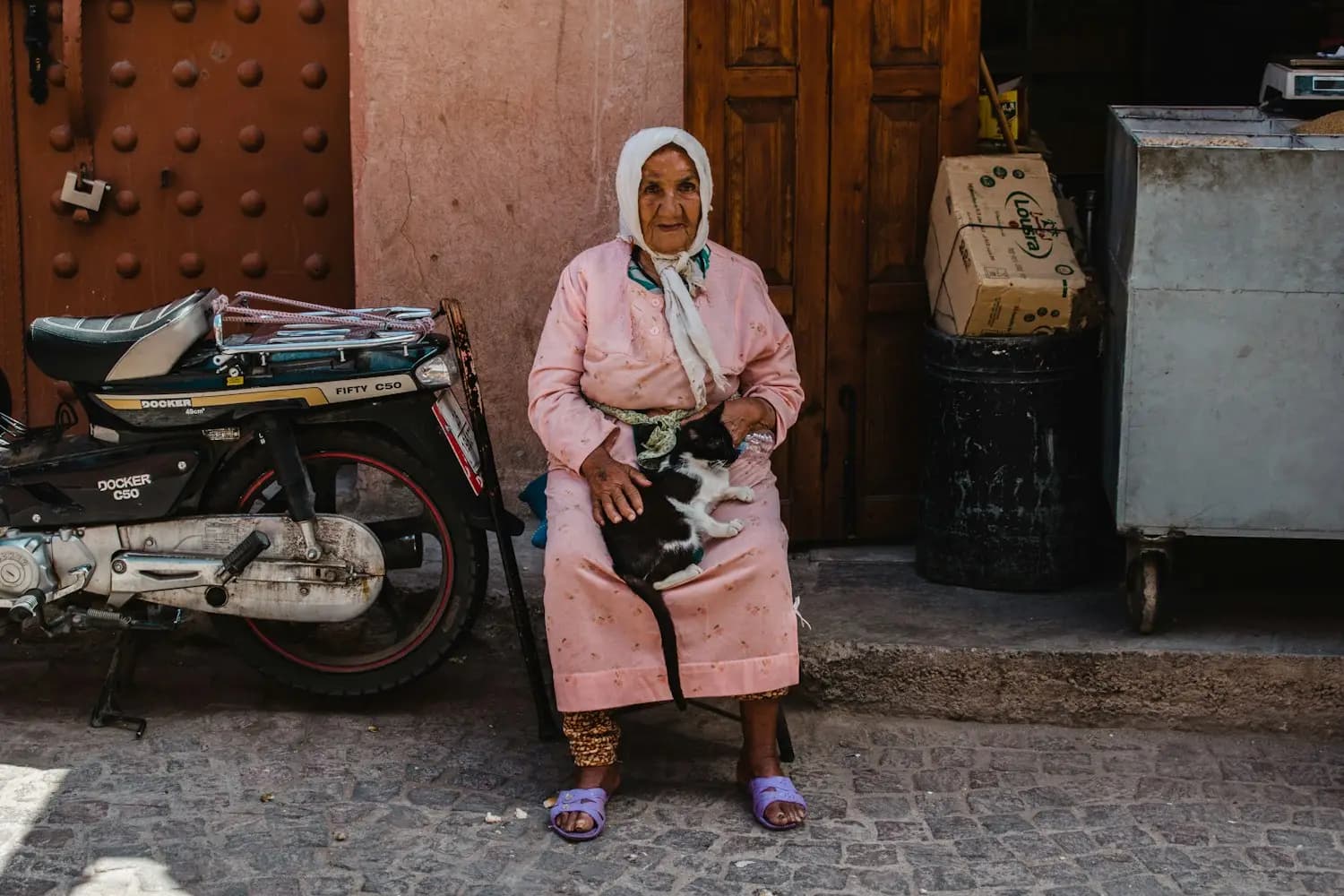 Une femme âgée assise devant une porte