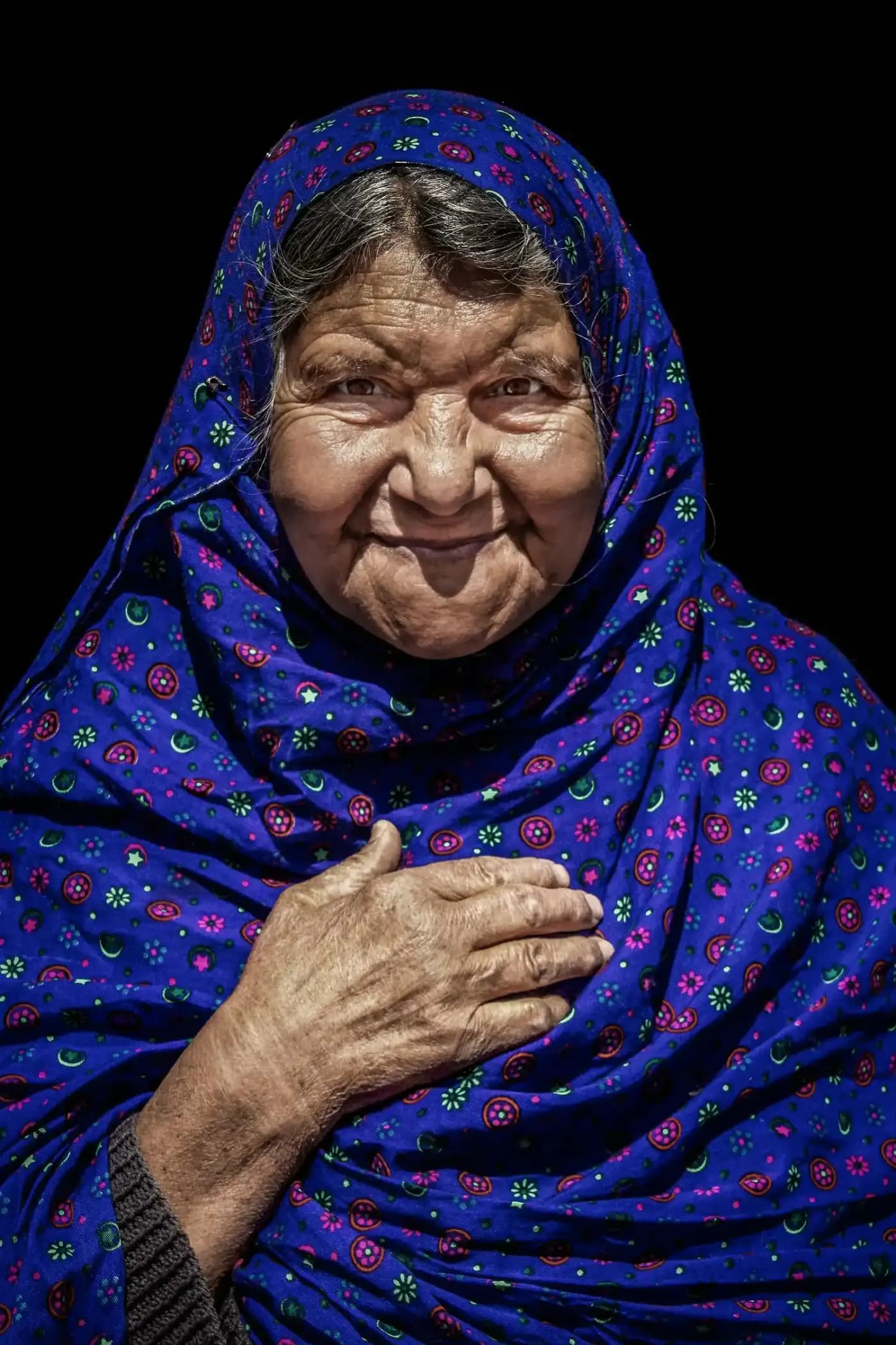 A grandmother in a blue headscarf smiles